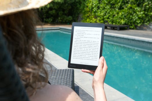 Woman reading eBook by pool